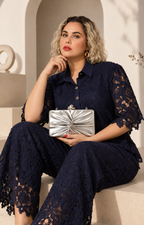 Bolsa clutch plateada con moño de la marca Boutiquemirel, estilo elegante y moderno, con cierre y detalles en brillo plateado.