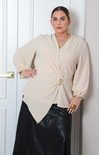 Blusa beige asimétrica para curvy de Boutiquemirel con detalle dorado, vista frontal mostrando el diseño elegante y moderno.