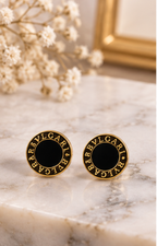 Set de aretes de broquel negro y dorado con cristal