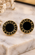 Set de aretes de broquel negro y dorado con cristal