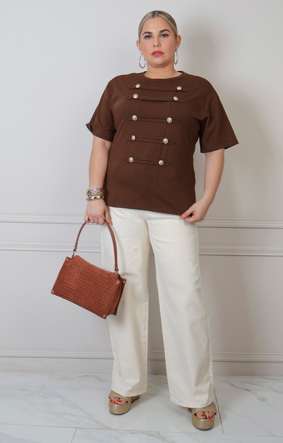 Blusa curva de Boutiquemirel con botones dorados estilo militar, de manga larga y diseño elegante en color neutro.