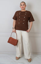 Blusa curva de Boutiquemirel con botones dorados estilo militar, de manga larga y diseño elegante en color neutro.