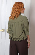 Blusa camisera regular de Boutiquemirel con olán inferior en tela ligera y color neutro, vista frontal.