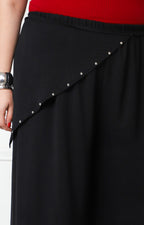Pantalón curvy asimétrico con aplicaciones en tejido negro y detalles decorativos, de la marca Boutiquemirel.