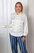 Camisa beige estilo militar con botones dorados de la marca Boutiquemirel, blusa regular con diseño elegante y detalles en el frente.