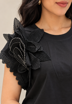Blusa negra con flor plisada en hombro
