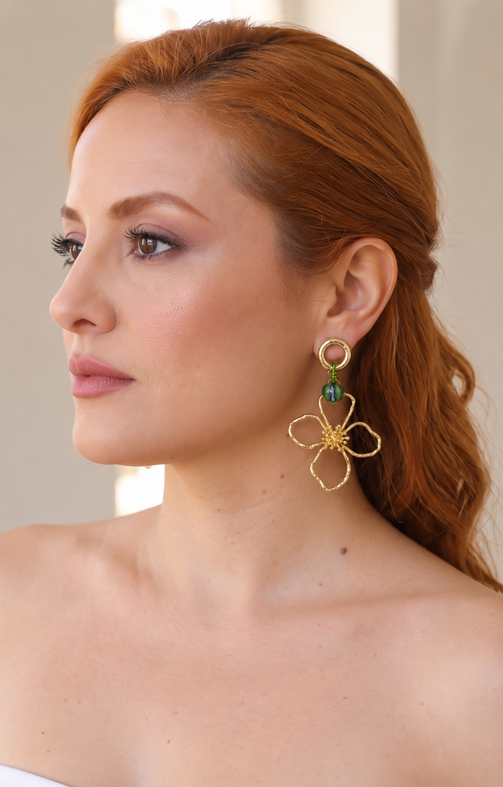 Aretes largos de flor dorada con piedra verde